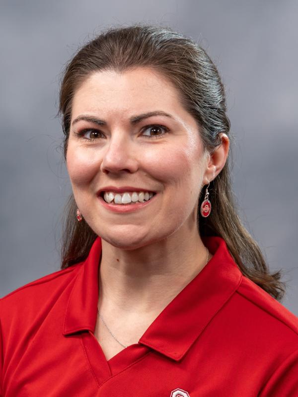 picture of Renee Benham, a beautiful white woman with long brown hair wearing a red Ohio State polo with Ohio State earrings. 
